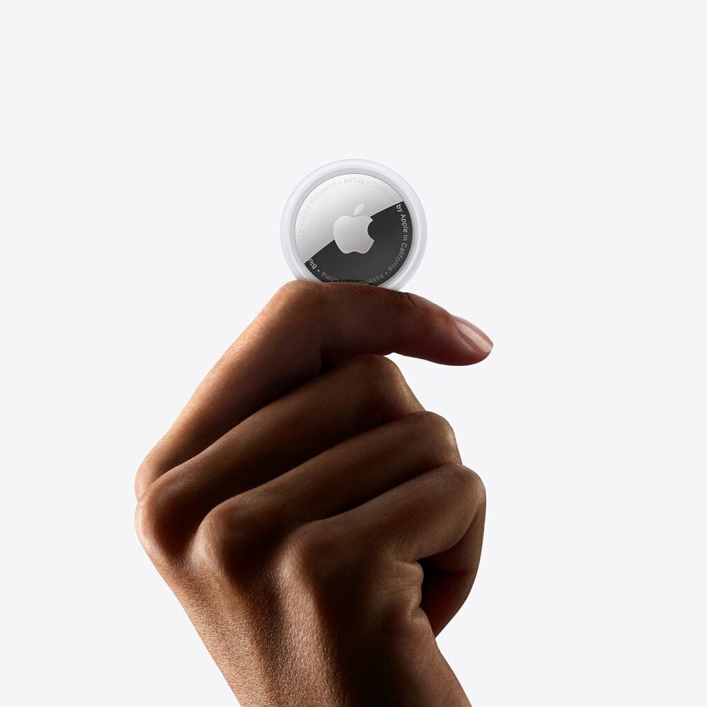 Hand holding an Apple AirTag, the subject of this review, showing its small circular design and Apple logo