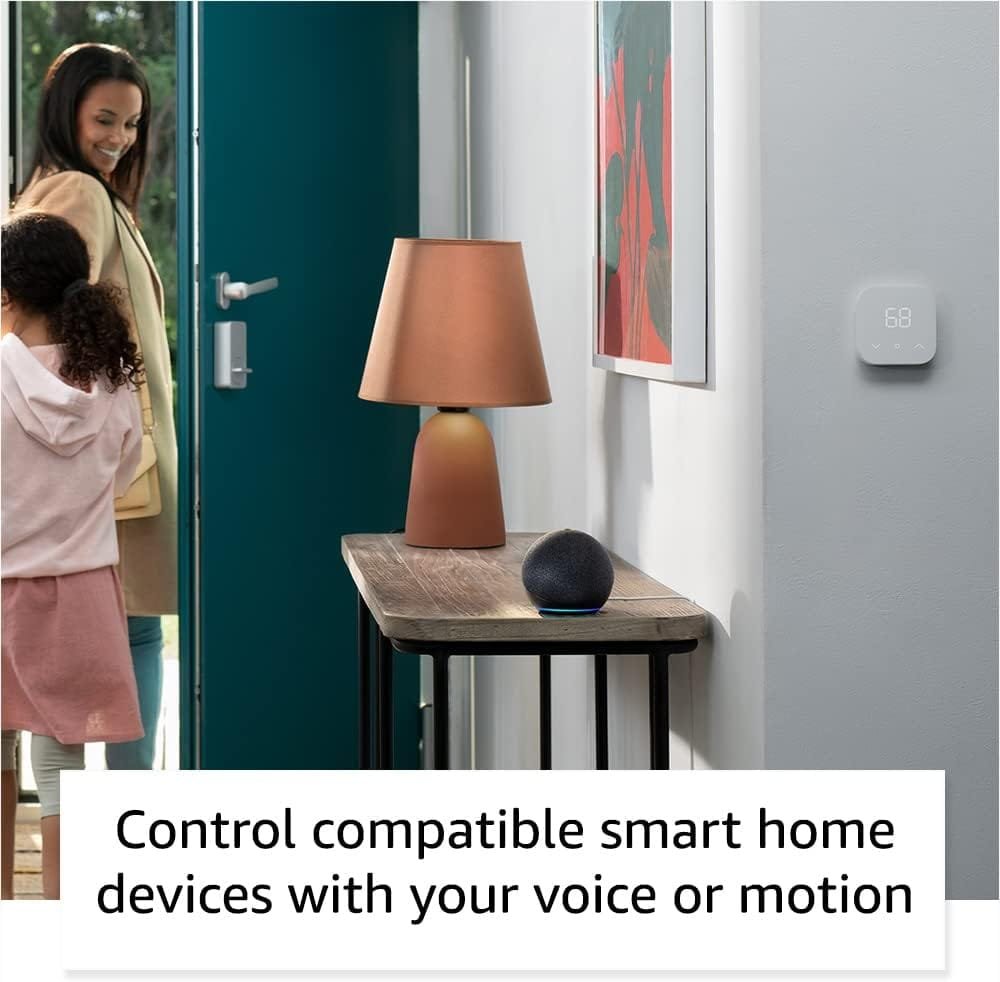 A woman and child exit a room with a console table holding a lamp and the Amazon Echo Dot 5th Gen smart speaker. A smart thermostat is on the wall near the door.